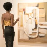 Black woman standing in front of a beautiful piece of modern art in a gallery | How to Buy Fine Art | Bon Vie magazine